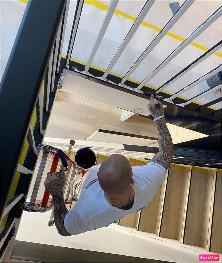 Schilder schildert veilig het trapgat op een ladder door middel van de Paintholder